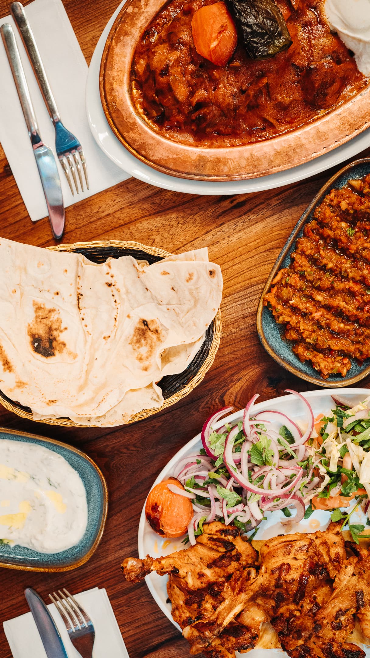 A table set with mezze, lavash and adana, top-down