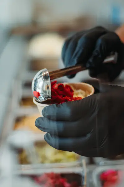 Black-gloved hands scooping pickled cabbage