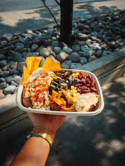 Takeout bowl held over a sidewalk and stones