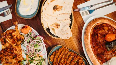 A table set with mezze, lavash and adana, top-down