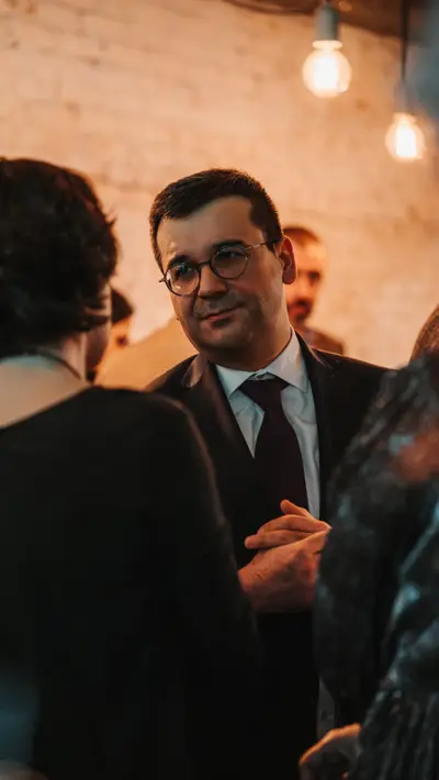 Guests in conversation against exposed brick with bulb lighting