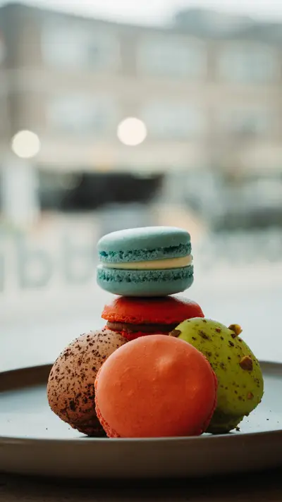 Macarons and a choux bun stacked on a small plate by the window