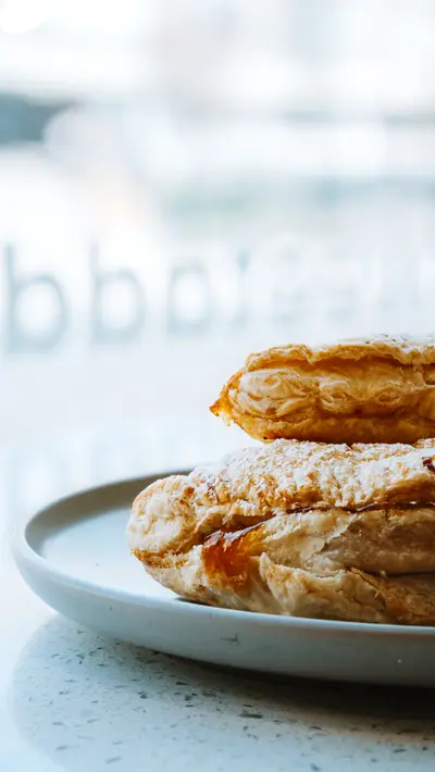 Layered apple pastries on a plate against the shopfront glass