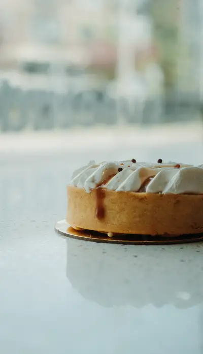 A caramel tart with a piped cream collar on a marble counter