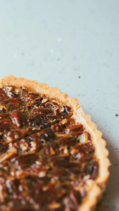 A pecan tart photographed from above on a pale surface