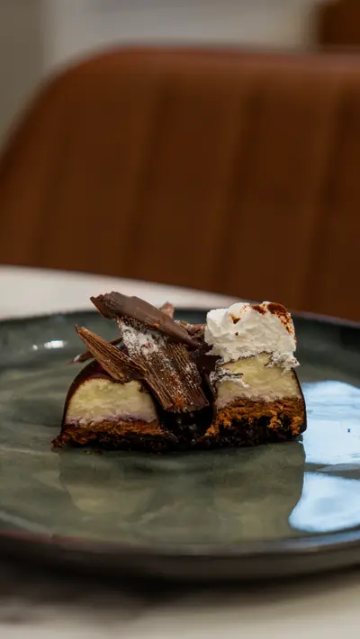A chocolate and cream slice on a green ceramic plate