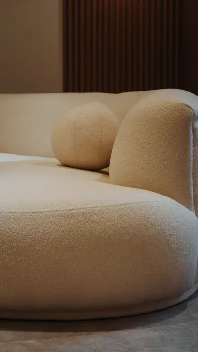 The curve of a boucle sofa against a fluted wall