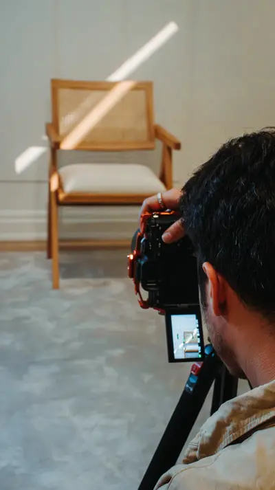 A photographer framing the cane chair on camera
