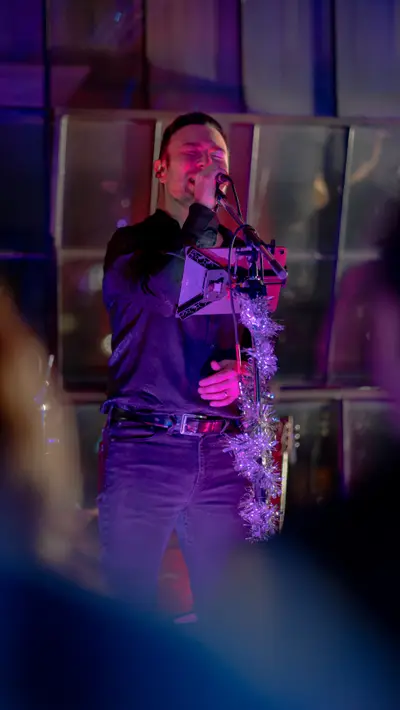 A performer singing under violet stage light