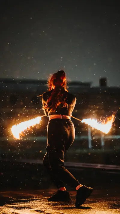 A fire dancer turning with two lit trails in the rain