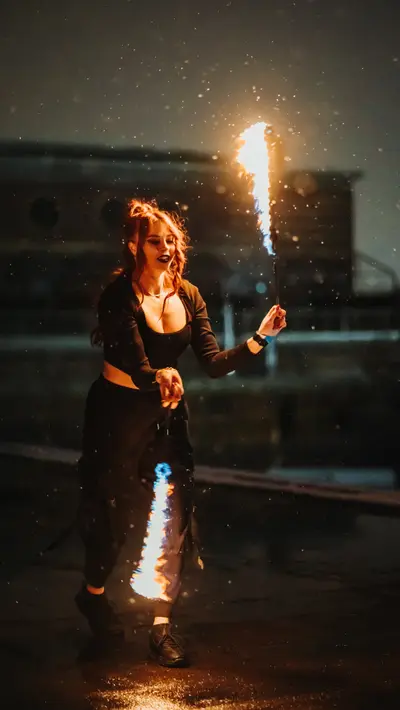 A fire performer holding a lit torch above the shoulder