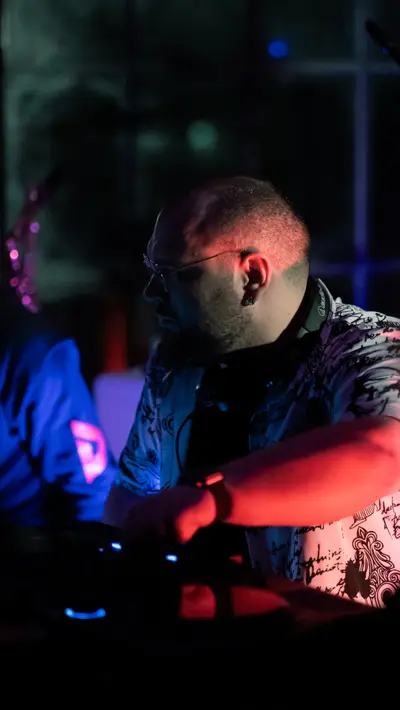 A DJ leaning over the mixer in blue light
