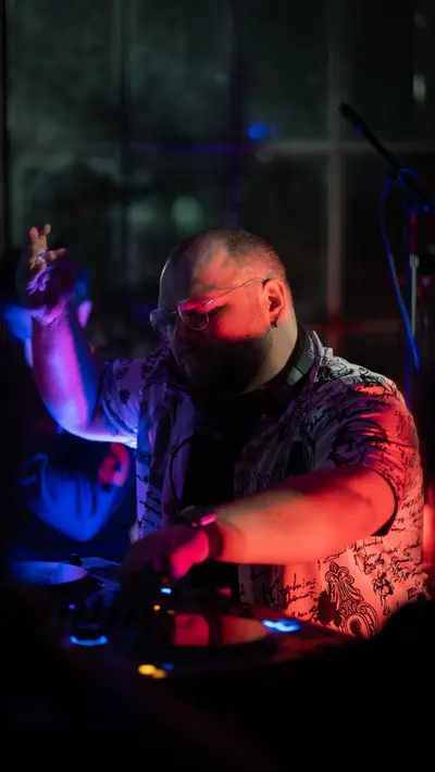 A DJ with both hands on the controls, lights behind