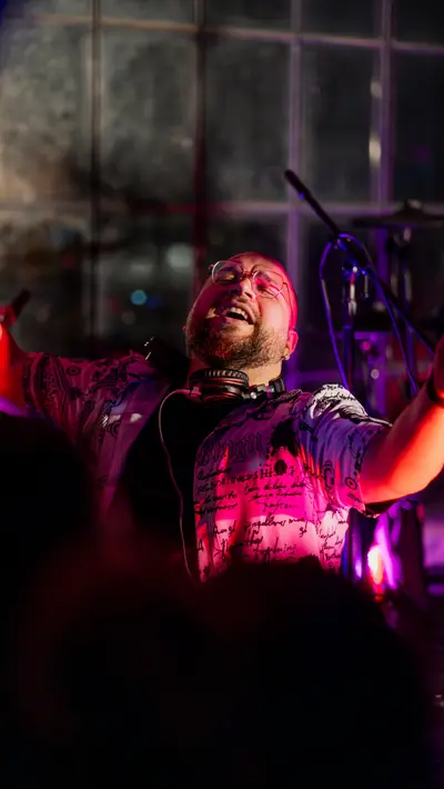 A DJ with arms spread wide over the crowd