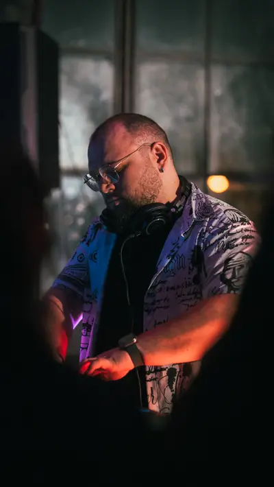 A DJ in headphones beside a warehouse window