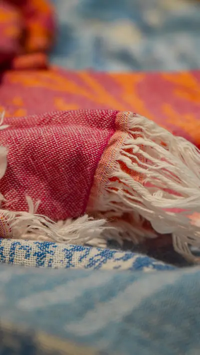 The knotted fringe of a pink towel over a blue one