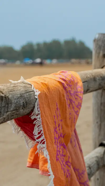 An orange towel draped over a weathered beach fence