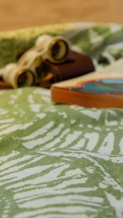 Binoculars and a book resting on a green printed towel