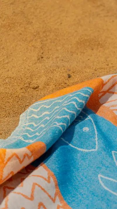 A fish-printed towel laid across the sand