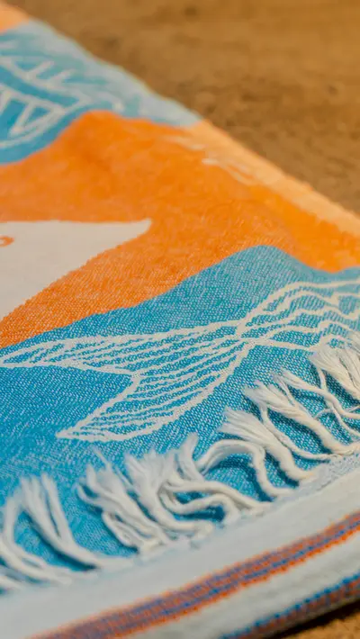 The fringed edge of a folded orange and blue towel