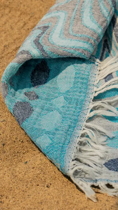 A rolled towel resting on the sand
