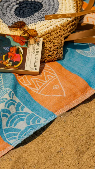 A straw bag, sunglasses and tag arranged on a towel