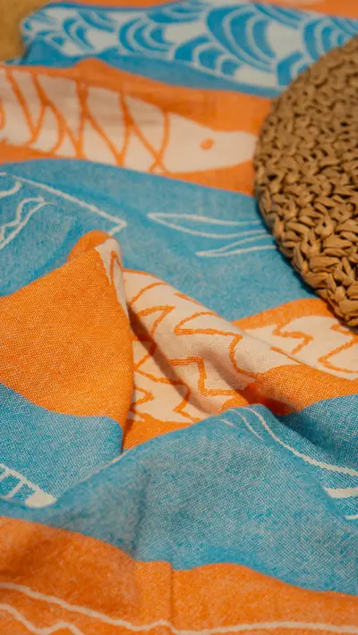 A woven disc resting on a folded fish-print towel