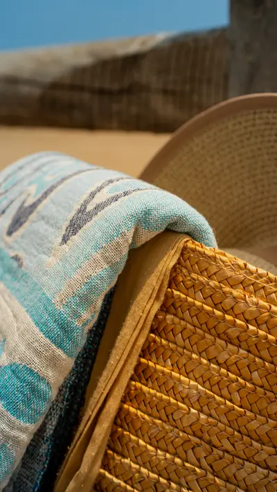 A hat, straw bag and towel together on the beach