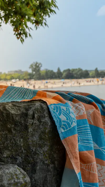 A towel draped over a rock with the shoreline behind