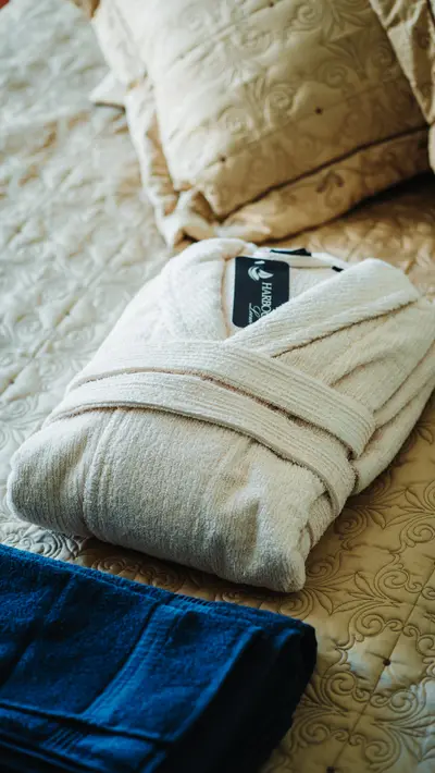 A folded cream robe with a blue one beneath on the bed