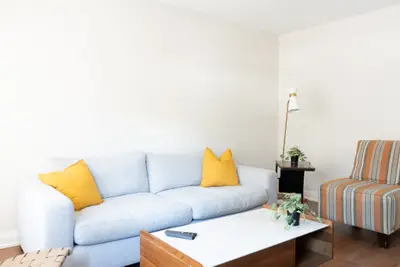 A living room with a white sofa, yellow cushions and striped chairs