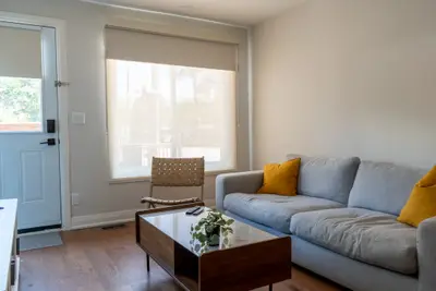 A grey sofa with yellow cushions beside the entry door