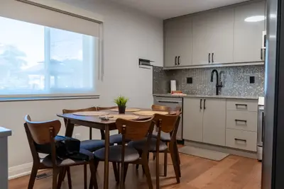 A dining table in front of a white galley kitchen