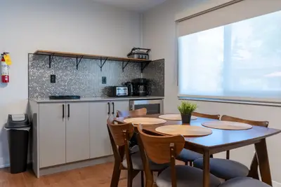 A galley kitchen with open shelf and dining table by the window