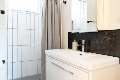 A bathroom vanity with dark splashback and shower curtain