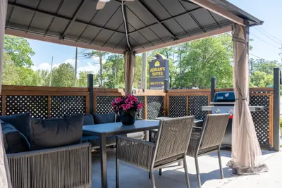 A covered gazebo with lounge seating and a dining table