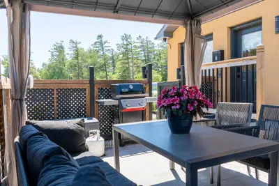 A patio table under the gazebo with barbecues beyond