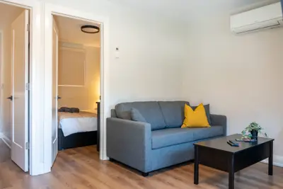 A sitting room with a grey sofa opening through to the bedroom