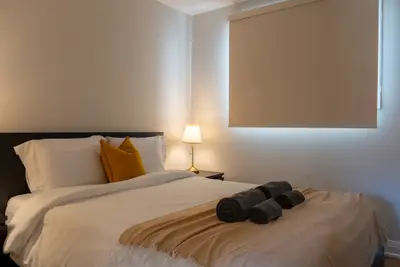 A queen bed with rolled towels and a bedside lamp