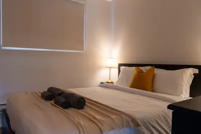 A bed with towels and a lit bedside lamp