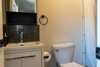 A bathroom basin, mirror and toilet beside the shower curtain