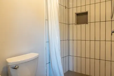 A tiled shower stall with the curtain drawn back