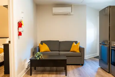 A grey sofa with yellow cushions beside the fridge