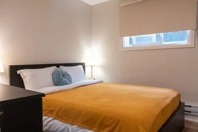 A bed with an ochre bedspread under a high window