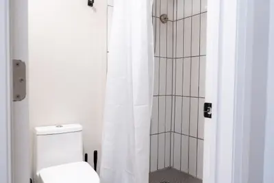 A shower with the curtain open beside the toilet