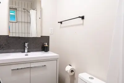 A white vanity with a slate splashback and mirror