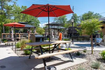 A picnic table under a red parasol in the courtyard