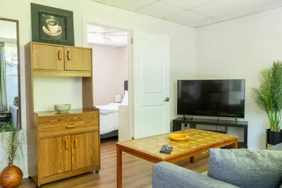 A living room with a wooden cabinet and the bedroom beyond