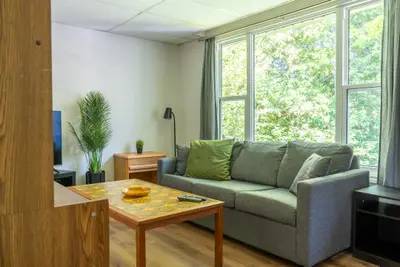 A green sofa and tiled coffee table by tall windows