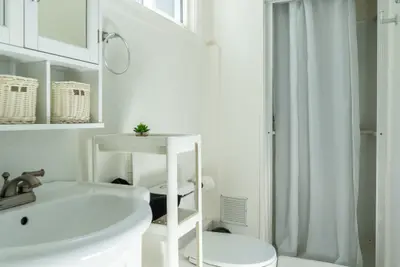 A small bathroom with baskets on the shelf above the basin